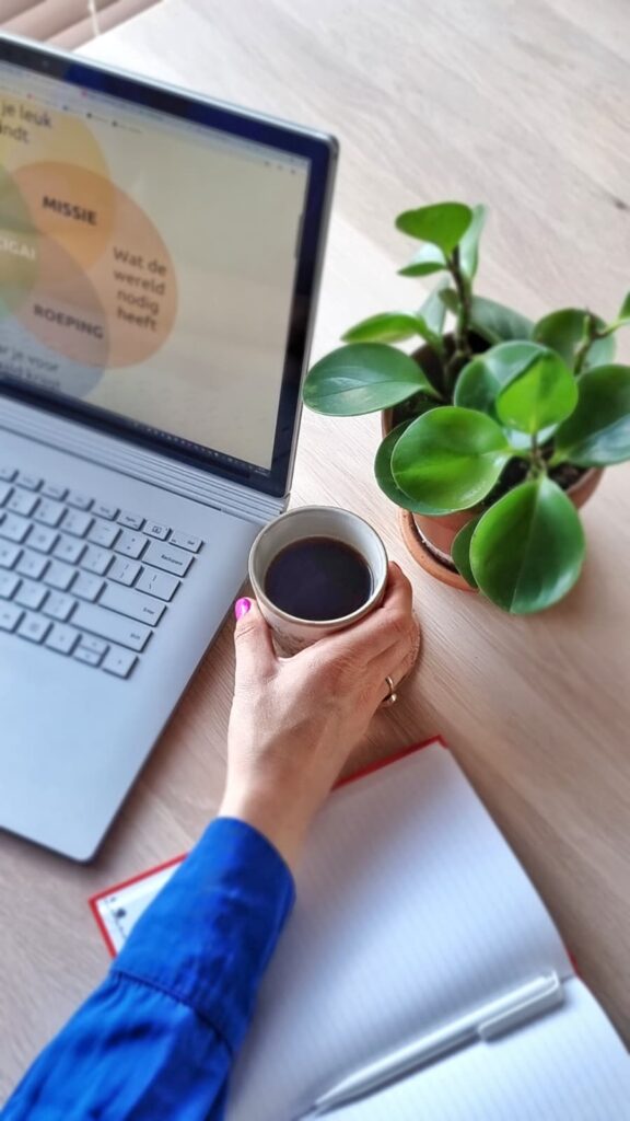 Foto van Myrthe Meulenbeek, eigenaar en loopbaancoach van Levensbrouwerij, met koffie, laptop, en notitieblok, klaar om mensen te begeleiden bij hun loopbaan