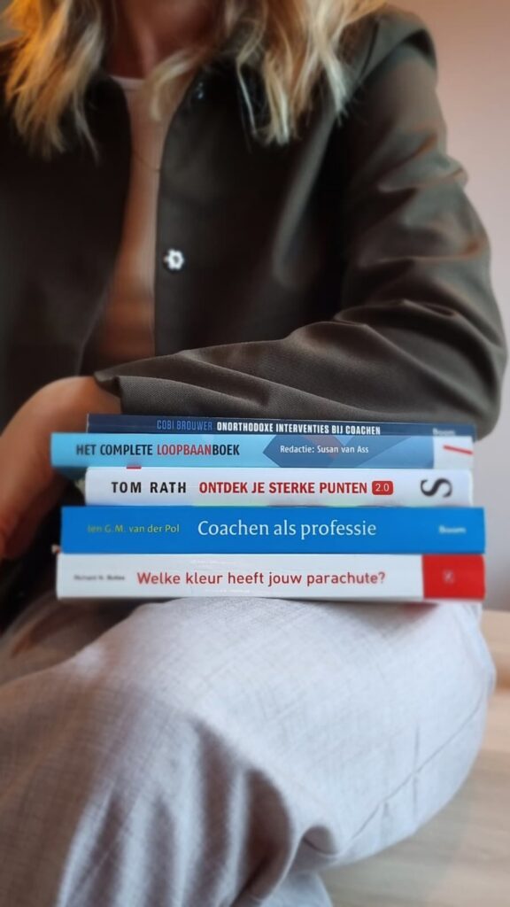 Foto van Myrthe Meulenbeek, eigenaar en loopbaancoach van Levensbrouwerij met stapel relevante boeken