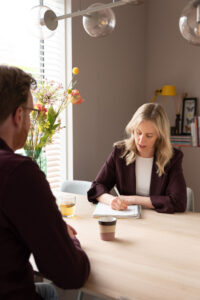 Foto van Myrthe Meulenbeek, Loopbaancoach, aan tafel met een client, terwijl ze aantekeningen maakt.